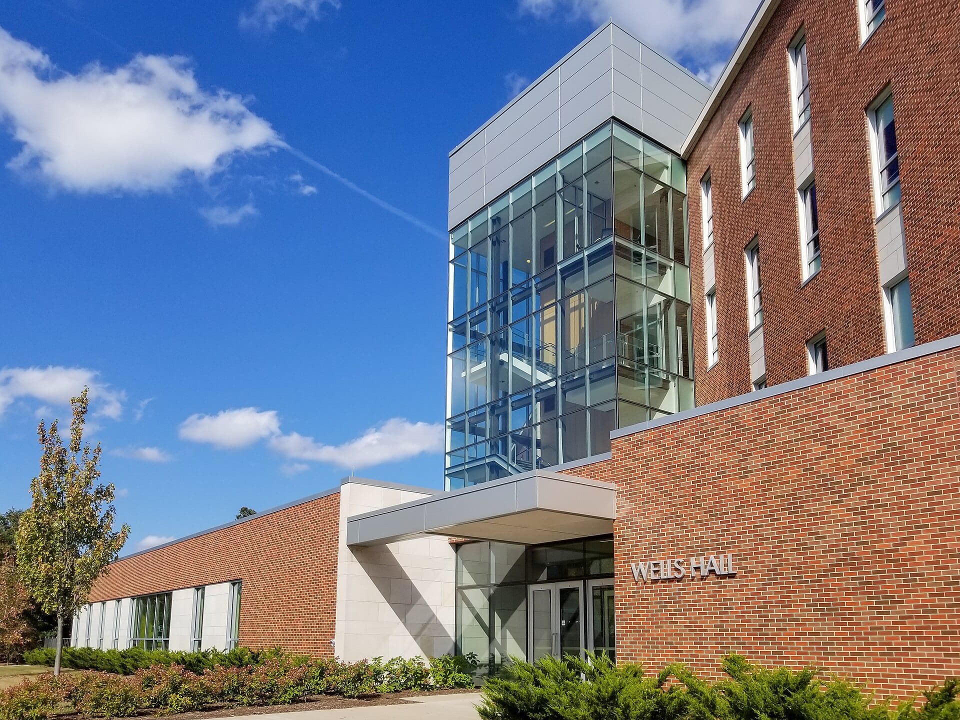 Wells Hall at Michigan State University with a glass stair tower beside red brick