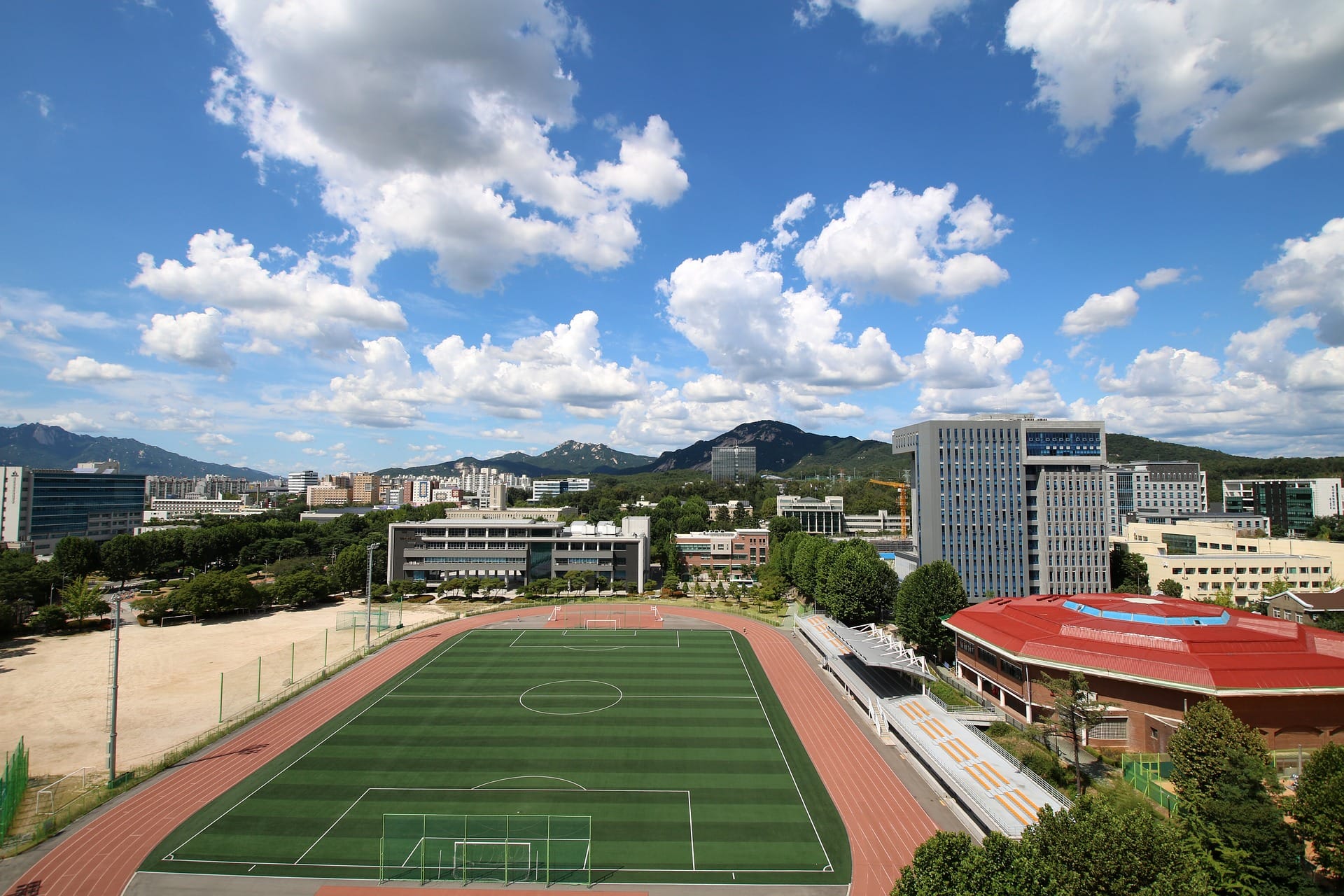 The campus of Seoul National University of Science and Technology with a sports field under a blue sky